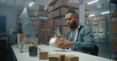 Afro-Amerikan lojistik müdürü akıllı telefon kullanarak paketleri tarıyor, postane deposunda çalışıyor. Sıralama merkezi çalışanı müşterilere karton kutular taşır. E-ticaret emirleriyle birlikte depolama.