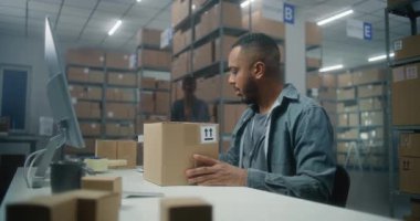 Afro-Amerikan depo görevlisi barkod tarayıcılı paketleri tarıyor, bilgisayar kullanıyor, postanede çalışıyor. Teslimat için müşterilere kutu taşıyan tasnif merkezi çalışanı. Lojistik dağıtım merkezi.