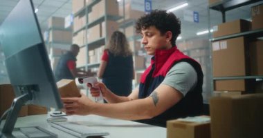 Envanter yöneticisinin barkod tarayıcı ile paketleri taraması, müşteriye nakliyeye hazırlanması, bilgisayarda çalışması. Depo çalışanları kutu taşıyor. E-ticaret mağazası veya posta servisi.