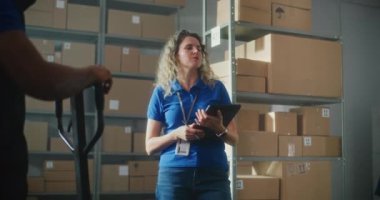 Tablet bilgisayarlı kadın envanter yöneticisi meslektaşlarına talimat veriyor. Depoda karton kutular, e-ticaret siparişleri ve ürünlerle çalışan çeşitli tasnif merkezleri çalışanları..