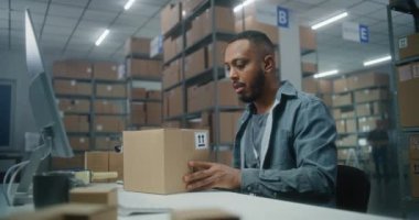 Posta servisi: Afrikalı Amerikalı lojistik uzmanı barkod tarayıcılı paketleri tarıyor, müşteriye teslimata hazırlanıyor, bilgisayar kullanıyor. Kutu taşıyan tasnif merkezi çalışanı. E-ticaret emirleri.