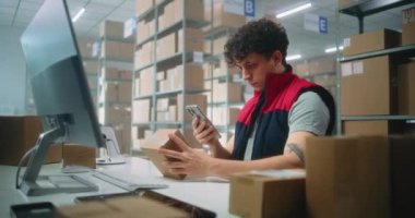 Lojistik müdürü akıllı telefon kullanarak küçük paketleri tarıyor, postanenin deposunda çalışıyor. Karton kutuları müşterilere teslim etmek için tasnif merkezi çalışanları. E-ticaret emirleriyle birlikte depolama.