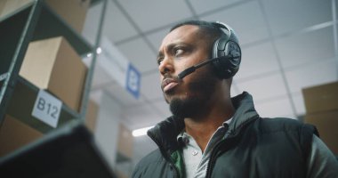 Afro-Amerikan Lojistik Koordinatörü, Müşteriye Kulaklık Takan Yönetici Depo Tesislerinde Tablet Bilgisayar kullanıyor. E-Ticaret Çevrimiçi Emirleri olan Lojistik Dağıtım Merkezi. Kapat..