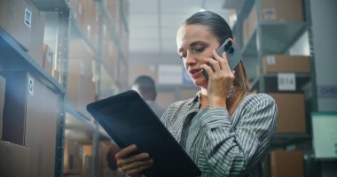 Kadın Müşteri Desteği Lojistik Uzmanı, Müşteriyle Telefonda Yönetici Görüşmeleri, Tablet Bilgisayar Kullanımı. Arka planda çalışan bir depo çalışanı. E-ticaret mağazasının teslimat servisi. Kapat..