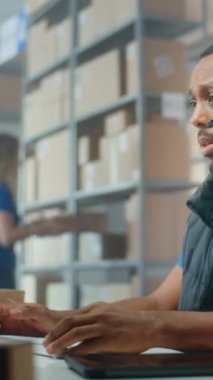 Afro-Amerikan lojistik koordinatörü. Müşteri ile telefon görüşmeleri yapıyor, bilgisayar kullanıyor, postanede ya da E-mağazasında çalışıyor. Karton kutular taşıyan tasnif merkezi çalışanları. Dikey video.