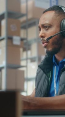 Müşteriyle kulaklık takan Afro-Amerikan lojistik koordinatörü, bilgisayar kullanıyor, postanede ya da e-ticaret deposunda çalışıyor. Teslimat için karton kutular taşıyan tasnif merkezi çalışanları.