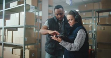 Kadın Lojistik Koordinatörü Depo Tesisindeki Tablet Bilgisayar 'ı takıyor, Afrikalı Amerikalı Yönetici İş Arkadaşına Yardım Ediyor. E-ticaret emirleriyle birlikte lojistik dağıtım merkezi. Doli Vuruşu.