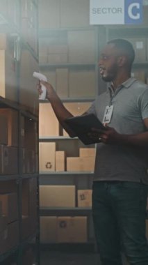 Afro-Amerikan Depo Ortaklığı, karton kutuları tarayıcı ile tarar, tablet bilgisayardaki bilgileri kontrol eder, teslimat paketini müşteriye götürür. E-Ticaret Mağaza Sıralama Merkezi. Dikey Çekim.