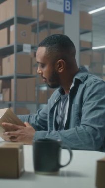 Posta servisi: Afro-Amerikan lojistik uzmanı barkod tarayıcılı paketleri tarıyor, müşteriye teslimata hazırlanıyor, dizüstü bilgisayar kullanıyor. Tasnif merkezi çalışanı kutu taşır. E-ticaret emirleri