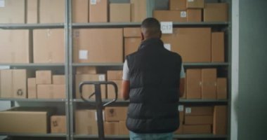 Afro-Amerikan çalışan kamyonu E-ticaret ürünleri paketleriyle yüklüyor. Kadın Depo Ortaklığı Tablet Bilgisayarlı Kulaklık Giyiyor. Teslimat Teslimat Merkezi. Doli Vuruşu.