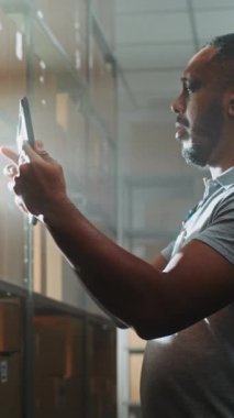 Afro-Amerikan Depo Ortaklığı Karton Kutuları E-Ticaret Online Siparişleri Tablet Bilgisayar kullanarak, Bilgileri Denetleyerek, Nakliye İçin Paket Ediyor. Teslimat Sıralama Merkezi. Dikey Çekim.