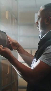 Afro-Amerikan Depo Ortaklığı Karton Kutuları E-Ticaret Online Siparişleri Tablet Bilgisayarını kullanarak, Paketler Nakliye Bilgilerini Denetler. Teslimat Hizmet Sıralama Merkezi. Dikey Çekim.