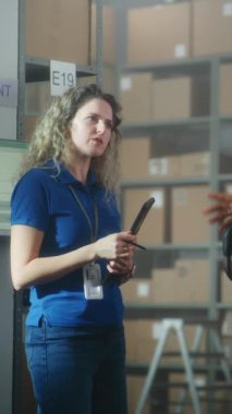 Tablet bilgisayarlı kadın lojistik müdürü iş arkadaşlarıyla konuşur, teslimat için talimat verir. Posta hizmetlerinin depolama tesisinde çalışan çok ırklı sınıflandırma merkezi çalışanları veya çevrimiçi mağaza