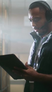 Kulaklıktaki Afro-Amerikan Envanter Yöneticisi paket sevkiyat bilgilerini kontrol etmek için Tablet Bilgisayar kullanıyor. E-Ticaret Çevrimiçi Emri ile Depo Tesisi. Teslimat Hizmet Sıralama Merkezi. Yavaş Hareket.