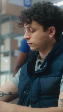 Erkek envanter müdürü bilgisayarda çalışır, barkod tarayıcılı paketleri tarar, müşteriye nakliye için paket hazırlar. Kutu taşıyan tasnif merkezi çalışanları. E-ticaret mağazası. Dikey video.