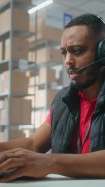 Kulaklıkla Afrikalı Amerikalı lojistik koordinatörünün portresi müşteriyle konuşuyor, posta servisinde ya da çevrimiçi depolamada dizüstü bilgisayarla çalışıyor, kameraya bakıyor. Sıralama merkezi çalışanları kutucukları işaretliyor