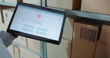 Postal Warehouse Associate, Karton kutunun QR kodunu barkod tarayıcı ile tarıyor, paket bilgisini kontrol ediyor. Tablet Bilgisayar Ekranı İzleme Uygulamasını İzleme Paket Yönlendirmesine Gösterebilir. Kapat..
