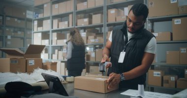 Afro-Amerikan Depo Tezgâhtarı, Online Order, Prepares Parcels for Shipping, Tarayıcı Kodu, Tablet Bilgisayar ile karton kutuya etiket yapıştırıyor. E-Ticaret Mağazası Sıralama Merkezi, Teslimat Servisi.
