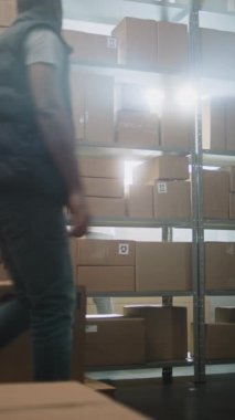 Erkek Afro-Amerikan Depo Ortaklığı Palet Yükü Tasnif Merkezi 'nde karton kutularla, E-Ticaret Çevrimiçi Siparişleri ile Ulaşım Paketleri Müşterilere Teslimat Malzemeleri. Dikey Çekim.