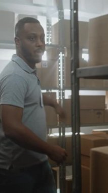 Afro-Amerikan Depo çalışanı Palet Kamyonu karton kutularla dolduruyor, Müşterilere Nakliye için Taşımacılık. E-Ticaret Çevrimiçi Siparişler ve Mallar Teslimat Merkezi. Dikey Çekim.