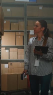 Depo Tesisindeki Tarayıcı kullanarak Online Gıda ile Kadın Envanter Yöneticisi Paketleri Tarıyor Tablet Bilgisayarda Nakliye Bilgilerini Denetler. Teslimat Hizmet Sıralama Merkezi. Dikey Çekim.