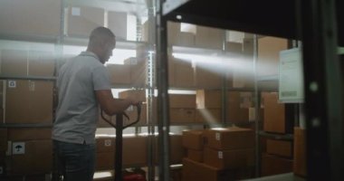 Afro-Amerikan tasnif merkezi çalışanı Palet Kamyonu, Karton Kutular, Raflara Paketler boşaltıyor. Depo Teslimat Teslimat Teslimatı E-Ticaret Online Siparişler, Mallar. Doli Vuruşu.