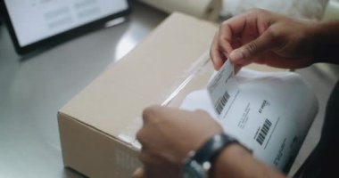 Afro-Amerikan Depo Kâtibi çevrimiçi siparişlerle paket üzerine etiket yapıştırıyor, tarama kodu, müşterilere nakliyeye hazırlanıyor. E-Ticaret Mağazası, Posta Teslimat Servisi. Kapat..