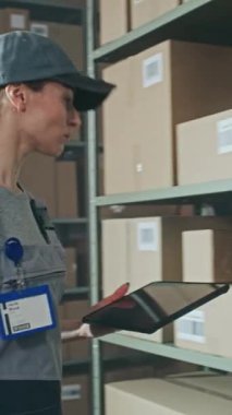 Kadın Depo İşçisi karton kutuları tarıyor E-Commerce Online ürünler rafta tarayıcı ile, Tablet Bilgisayar kullanarak, kargo için paket alıyor. Teslimat Teslimat Merkezi. Dikey Çekim.