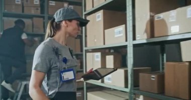 Kadın Depo İşçisi karton kutuları tarıyor E-Commerce Online Gıda ile rafta tarayıcı ile, Tablet Bilgisayar kullanarak, Nakliye için paket alıyor. Teslimat Teslimat Merkezi. El bilgisayarı