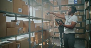 İleri Teknoloji Modern Depo: Fütürist Tam Vücut Robotik Dış iskelet Giyen İşçi Rafa Karton Kutusunu Yerleştirdi. Afro-Amerikan Lojistik Uzmanı Tarayıcı Paketi Tablet Bilgisayar Envanterini Kontrol Ediyor