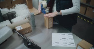 Depo Katibi, içinde Online Order, Tarama Kodu, Tablet Bilgisayar, Müşterilere Göndermeye Hazırlık Paketleri olan Karton Paketler. E-Ticaret Mağazası, Posta Teslimat Servisi. Kapat.