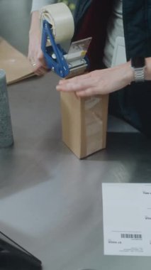 Depo Katibi, içinde Online Order, Tarama Kodu, Tablet Bilgisayar, Nakliyeye Hazırlık Paketleri olan karton kutular. E-Ticaret Mağazası, Posta Teslimat Servisi. Dikey Çekim.