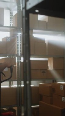 Afro-Amerikan tasnif merkezi çalışanı Palet Kamyonu, Karton Kutular, Raflara Paketler boşaltıyor. Teslimat Deposu Alışveriş Tesisleri E-Ticaret Çevrimiçi Siparişler, Mallar. Dikey Çekim.