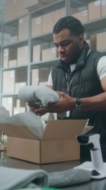 Afro-Amerikan Depo Tezgâhtarı, Online Order, Prepares Parcels for Shipping, Tarayıcı Kodu, Tablet Bilgisayar ile karton kutuya etiket yapıştırıyor. E-ticaret mağazası, teslimat servisi. Dikey Çekim.