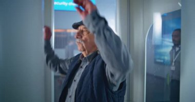 International Airport Terminal: Elderly Man Walks Through Metal Detector Scanner Gates on Security Checkpoint for Boarding Plane Flight. Queue of Diverse Passengers, Tourists Going on Vacation Trips.