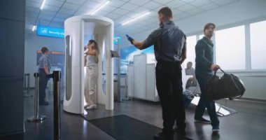 Havaalanı Terminali 'nde güvenlik kontrolü Metal Detektör Kapıları' ndan geçen çeşitli insanlar uçak uçuşu için. Güvenlik görevlisi yolcuların taranmasını denetliyor. Gezginler Grubu Seyahate Çıkıyor.