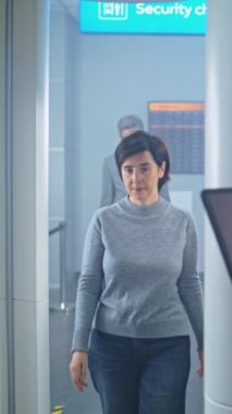 Havaalanı: Kadın, Metal Detektör Tarayıcıdan Geçerek Biniş Uçağı için Güvenlik Kontrol Noktasında. Güvenlik Subayı, Tablet Bilgisayar 'daki Yolcuları Denetliyor. Dolly Shot. Dikey Çekim.