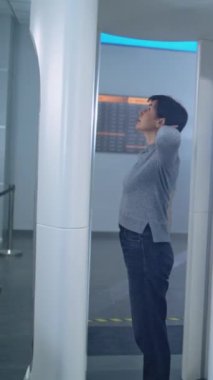 Havaalanı Terminali: Kadın, Metal Detektör Tarayıcısından Güvenlik Kontrol Noktasında Geçiyor. Bayan Güvenlik Subayı, Yolcuyu Uçuş için teftiş ediyor. Tatil gezilerine çıkan gezginler. Dikey Çekim.