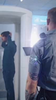 Havaalanı Terminali: Adam Metal Detektör Tarayıcısından Güvenlik Kontrol Noktasında Geçiyor. Güvenlik subayı evrakları, biletleri, uçuş yolcularını kontrol eder. Seyahate çıkan gezginler. Dikey Çekim.