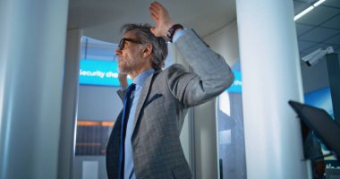 Havaalanı Terminali: Olgun Adam, Metal Detektör Tarayıcısından Güvenlik Kontrol Noktasında Geçiyor. Güvenlik Subayı, Yolcu teftişini kontrol ediyor. Çeşitli Gezginler Tatile Çıkıyor.