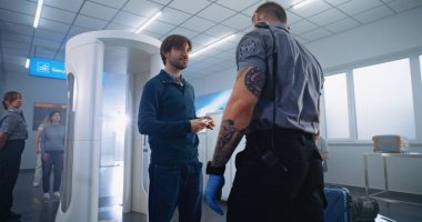 Havaalanı Terminal Güvenlik Kontrolü: Yetişkin Adam, Turist Metal Detektör Kapılarından Geçiyor. Güvenlik görevlisi, Yolcu 'yu yolcu uçuşu için kontrol ediyor. Çeşitli Gezginler Tatile Çıkıyor.