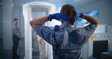 Havaalanı Güvenlik Kontrol Noktası: Uçak Uçuşu için Yolcu Taraması yapan Kadın Güvenlik Görevlisinin Arka Görünümü. Metal dedektör kapısından geçen kadın. Çeşitli Turistler Tatile Çıkıyor.