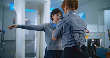 Havaalanı Terminali: Yetişkin Kadın, Metal Detektör Tarayıcısından Güvenlik Kontrol Noktasında Geçiyor. Bayan Güvenlik Subayı, Yolcuyu Uçuş için teftiş ediyor. Çeşitli Gezginler Tatile Çıkıyor.