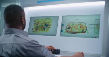 Afrikalı Amerikalı Güvenlik Subayı Modern Yazılım kullanarak Bilgisayar Monitörlerinde Bavul Gösterimini Denetliyor. Uçak Uçuşu için havaalanı güvenlik kontrol noktasındaki konveyör bandında gelişmiş X-ray taraması. Arka Görünüm