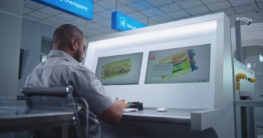 Havaalanı Güvenlik Kontrol Noktası: Afro-Amerikan Güvenlik Subayı PC Monitörlerinde X-ray Bavul Buluyor, Telsiz ile Bilgi Veriyor. Arka Görünüm.