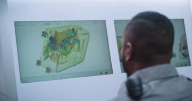 Havaalanı Güvenlik Kontrol Noktası: Bilgisayarda bagaj taraması yapan Afrikalı Amerikan Güvenlik Subayı 'nın arka görüntüsü. X-ray Tarama Teknolojisi Uçak Uçuşu için Modern Yazılım Gösteriliyor.