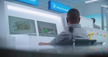 Havaalanı Terminali: Afrikalı Amerikan Güvenlik Subayı Bilgisayar ekranlarında bagaj taraması yapıyor. Bordalama Uçuşu Güvenlik Kontrol Noktasında Modern X-ray Tarama Teknolojisi.