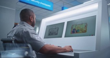 Havaalanı Güvenlik Kontrol Noktası: Afro-Amerikan Güvenlik Subayı Bilgisayar ekranlarında bagaj taramasını izliyor, Bavul Yazılımında Şüpheli Nesne Buluyor. Gelişmiş X-ray Tarama Teknolojisi.