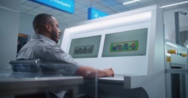 Modern Programı kullanarak, Afrikalı Amerikan Güvenlik Subayı, Bilgisayar Monitörlerindeki Bavul Gösterimini Denetliyor. Uçak Uçuşu için havaalanı güvenlik kontrol noktasındaki konveyör bandında gelişmiş X-ray taraması. Doli Vuruşu