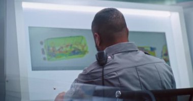 Modern Yazılım kullanarak bilgisayar monitörlerindeki bavul taramasını kontrol eden Afrikalı Amerikan Güvenlik Subayı 'nın arka görüntüsü. Havaalanı güvenlik kontrol noktasında gelişmiş X-ray tarama teknolojisi..